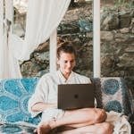 A woman sitting comfortably on a sofa using a laptop, depicting a serene remote work setup.