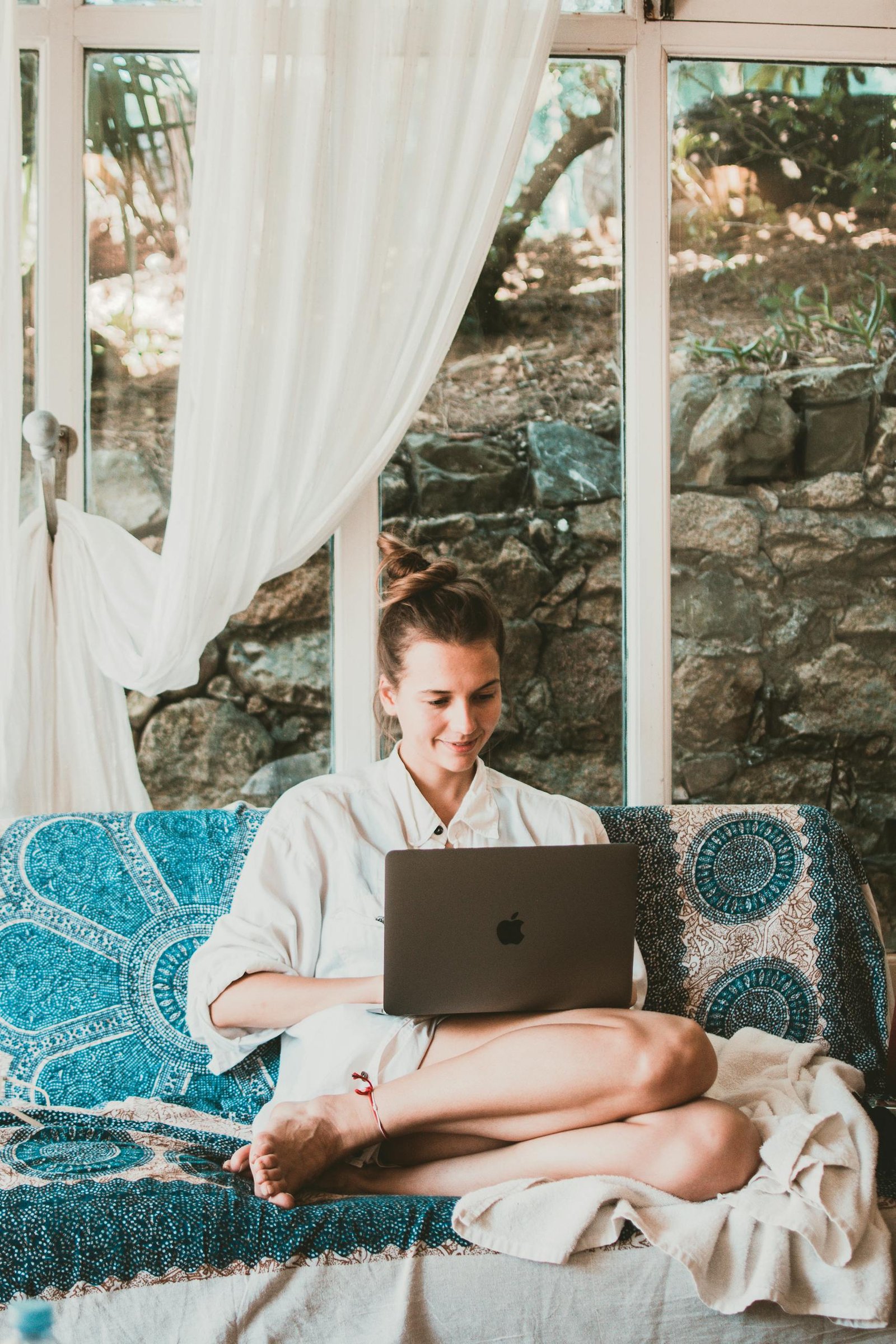 A woman sitting comfortably on a sofa using a laptop, depicting a serene remote work setup.