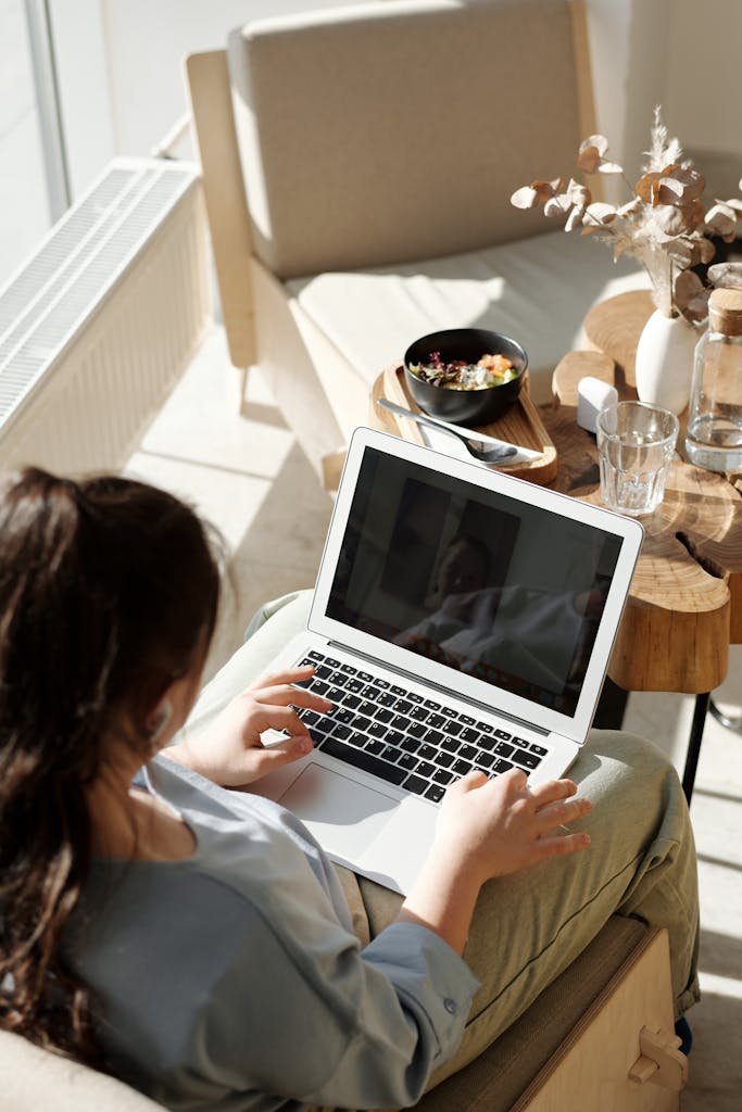 Woman enjoying remote work on a laptop in a cozy home setting with natural light. Why budgets don't work.