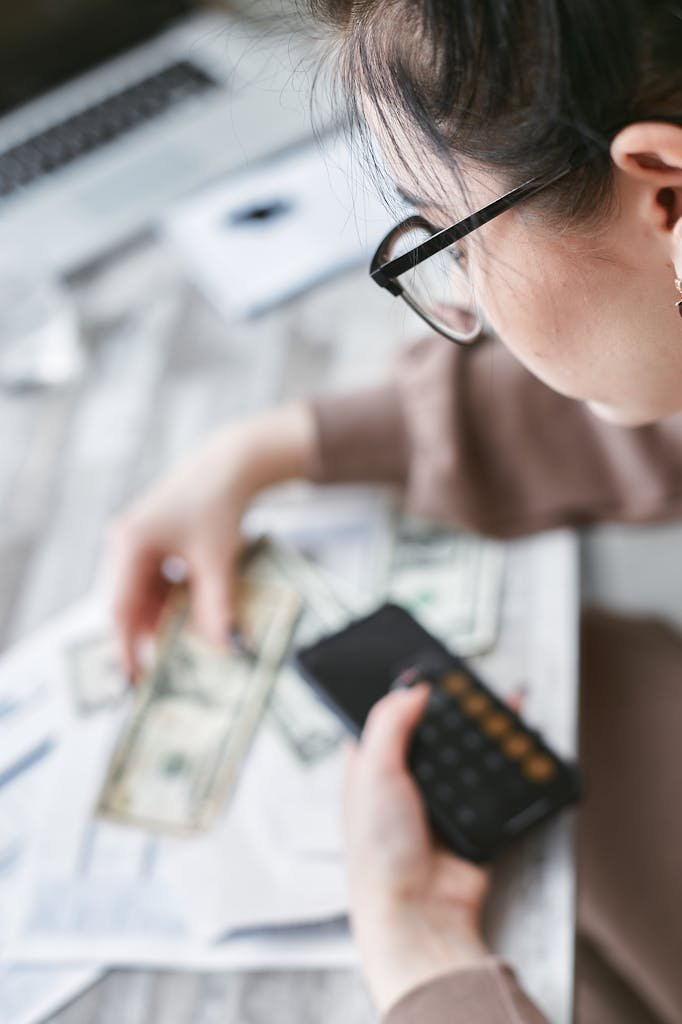 A woman calculates finances using a calculator with banknotes and documents on the table. Things I Spend Money On