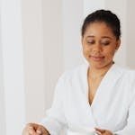 An African American woman enjoys a quiet moment with coffee at a modern office desk.