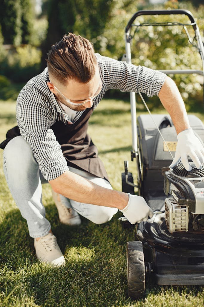 Man in a garden repairing lawn mower on sunny day, ideal for gardening and maintenance themes.