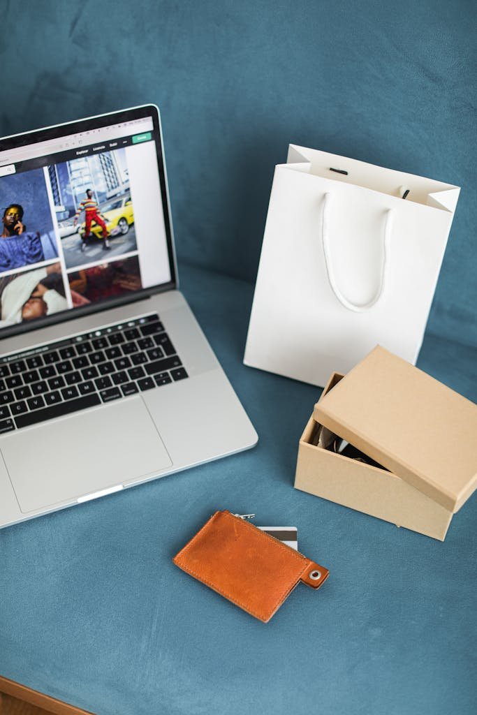 A high-angle view of online shopping items including a laptop, gift bags, and wallet on a blue surface. payment plan culture