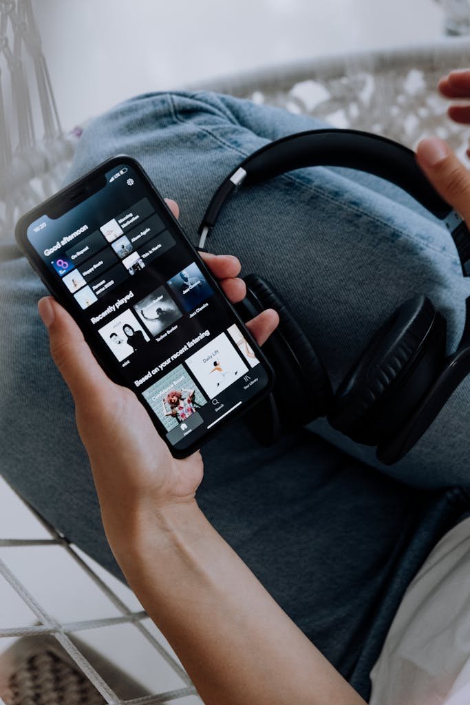Close-up of a person holding a smartphone with headphones, browsing a music app. Subscription trap