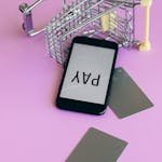 Smartphone and credit cards on a pink background illustrating digital payment and online shopping concept.