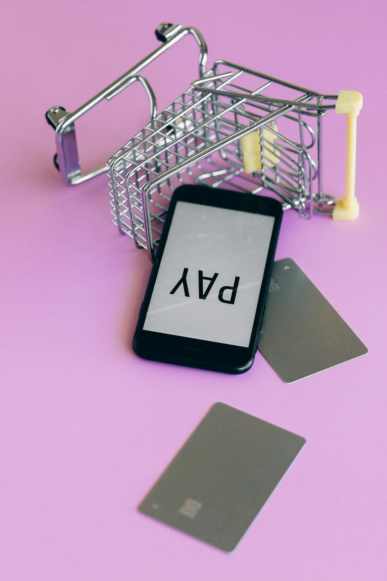 Smartphone and credit cards on a pink background illustrating digital payment and online shopping concept.