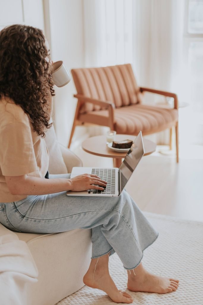 Woman enjoying coffee while working on a laptop in a warm, minimalist living room setting. hsa tax benefits